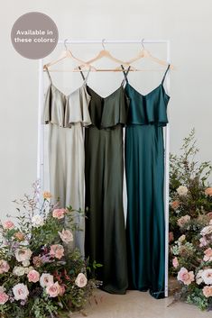 three bridesmaid dresses hanging in front of flowers