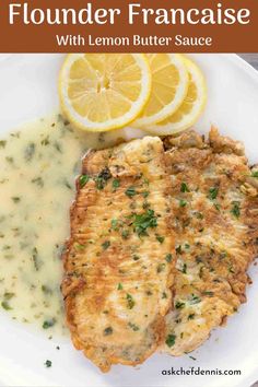 a white plate topped with fish covered in gravy next to lemon wedges