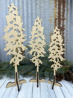 three wooden trees are standing next to each other in front of pine cones and evergreen needles