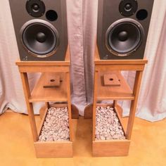 two speakers sitting side by side in front of a white curtain with rocks under them