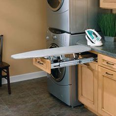 an ironing board is sitting on top of a dryer in the middle of a kitchen