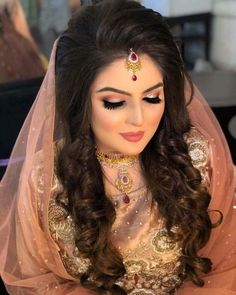 a woman with long hair wearing a bridal veil and gold jewelry on her head