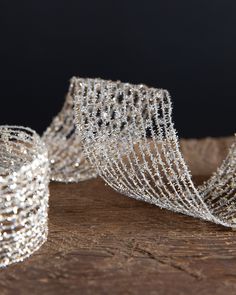 two rolls of silver wire sitting on top of a wooden table next to each other