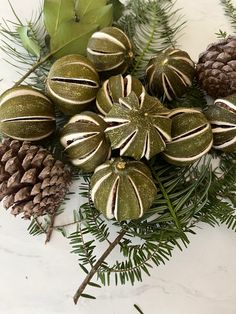 christmas ornaments and pine cones on a marble table top with greenery, leaves and branches