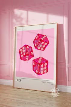 three pink dices sitting on top of a wooden floor in front of a pink wall