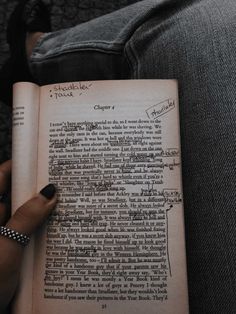 a person holding an open book with writing on it in their lap and her hand