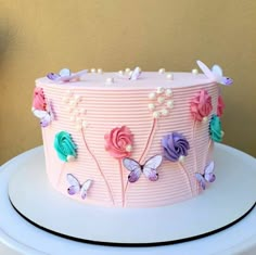 a pink cake decorated with flowers and butterflies