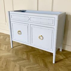 a white dresser with two drawers and gold handles