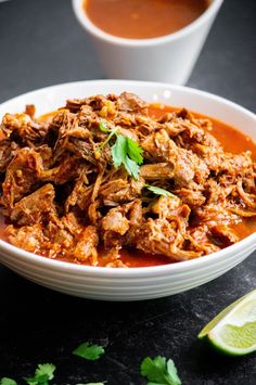 a white bowl filled with meat and garnished with cilantro