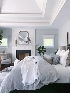 a bed with white linens and pillows in a bedroom next to a fire place