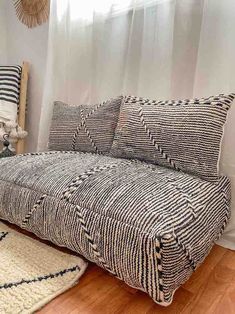 a bed with black and white striped sheets in a room next to a wooden floor