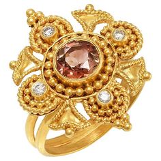 Flower shape Byzantine ring handcrafted in 22Kt yellow gold, featuring a Tourmaline center and a brilliant cut diamond in each petal. This breathtaking ring is created using the traditional techniques of filigree and granulation. Minute gold beads create the elegant shape of the flower petals while the delicate and intricate wire ornamentation transforms the gold into leaves. This unique ring belongs to Odyssea Collection: A collection inspired by the ancient Greek heritage, its timeless beauty Byzantine Ring, Greek Heritage, Byzantine Rings, Byzantine Jewelry, Choker Necklace Designs, Tourmaline Ring, Flower Ring, 22k Gold, Flower Shape