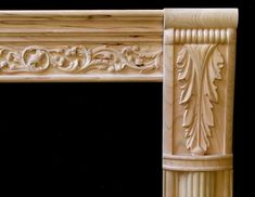 an ornate carved fireplace mantel with columns and leaves on the top, along with a black background