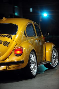 a yellow vw bug parked on the street at night