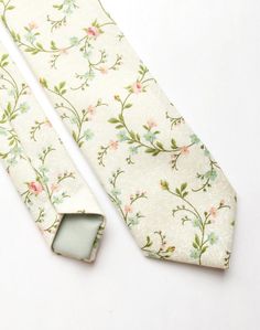 DESCRIPTION: This lovely men's skinny tie has been handmade using an ivory cotton with a pink and green floral print.  FABRIC: Cotton. LINING FABRIC: Cotton. -------------------------------------------------------------------------------------------- DETAILS: * Made the traditional way with fabric cut on the bias * Each tie has canvas lining throughout * Fabric lining just at the tip on each end of the tie * Width at the widest part measures approx 2.5 inches * The length of each tie is approx 5 Elegant Cotton Ties For Spring, Elegant Cotton Suit And Tie Accessories For Summer, Elegant Cotton Ties For Gifts, Spring Cotton Ties For Black Tie Events, Dapper Formal Ties For Spring, Dapper White Suit And Tie Accessories For Summer, Dapper Spring Formal Ties, Elegant Green Suit And Tie Accessories For Spring, Dapper Adjustable Ties For Spring