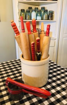 a bucket filled with lots of different types of cooking utensils on top of a checkered table cloth