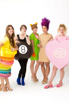 four women dressed in costumes posing for the camera with one holding a heart shaped balloon