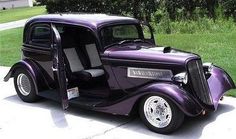 an old purple car is parked in the driveway