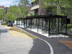 a bus stop with bikes parked in it on the side of the road next to a building