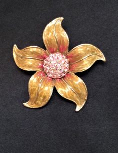 "This is a vintage pre-owned flower brooch.  This pretty flower has gold enamel petals with pink enamel details that highlight the sparkling pink center rhinestones. Each petal is detailed with a fine glittering gold tone outline. The brooch measures 2.5\" in diameter and has a secure rollover clasp. The brooch is in wonderful condition and will look fabulous on a jacket or little black dress. Thank you for looking!  Please remember this is a vintage item and as with all vintage jewelry, there w Pink Flower Enamel Pin, Vintage Pink Enamel Brooch Pin, Vintage Pink Enamel Pin Brooch, Pink Flower Enamel Brooch, Collectible Gold Flower Enamel Pin, Vintage Pink Enamel Brooches, Pink Details, Pretty Flower, Pink Enamel