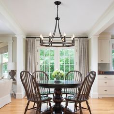 a dining room table with four chairs and a chandelier hanging from the ceiling