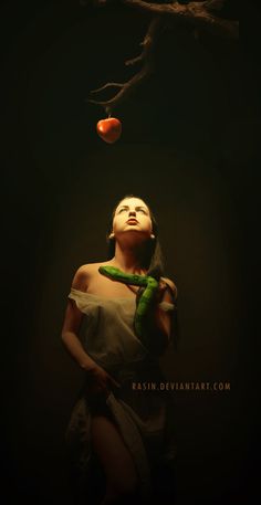 a woman is standing under a tree with an apple hanging from it's branch