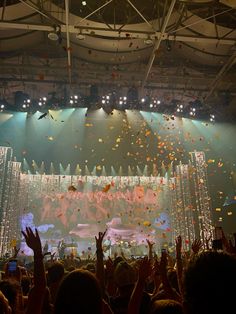 a large crowd at a concert with confetti falling from the ceiling