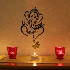 two red candles sitting on top of a table next to an elephant wall decal