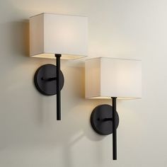 two lamps mounted on the wall next to each other, one is white and the other is black