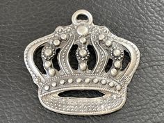 a silver metal crown sitting on top of a black leather surface