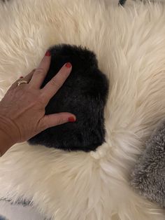 a woman's hand touching the fur on top of a white and black rug