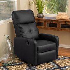 a black recliner chair sitting on top of a rug in front of a window