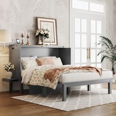 a bed sitting in a bedroom next to a dresser and lamp on top of a hard wood floor