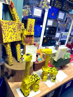 some giraffes made out of construction paper on a table in a classroom