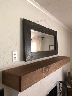 a mirror hanging on the wall above a fire place in a room with white walls