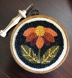 a close up of a needle on a wooden table with a flower design in the center