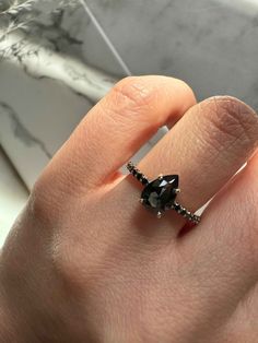 a woman's hand with a black diamond ring on it