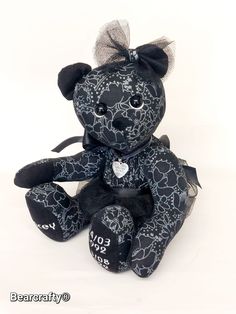 a black and white teddy bear with hearts on it's chest sitting in front of a white background