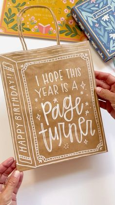 two hands holding a brown paper bag that says, i hope this year is a page turner