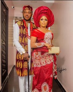 a man and woman dressed in traditional african garb standing next to each other on a hallway