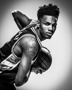 a black and white photo of a basketball player with tattoos on his arm holding a ball