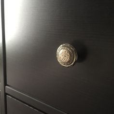 a close up of a black cabinet with a metal knob on the front and bottom