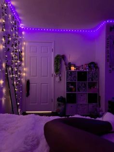 a bedroom with purple lights on the walls and a bed in front of a white door