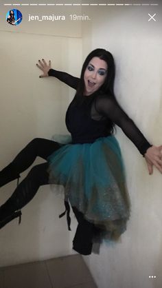 a woman dressed in black and blue posing for the camera with her legs spread out