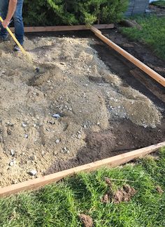 a man is shoveling dirt into a garden bed