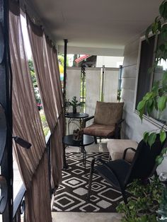 a patio with chairs, tables and curtains on the windowsill in front of it