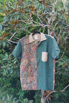 an old shirt hanging on a tree branch with leaves and branches in the foreground