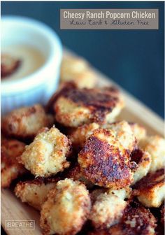 cheesy ranch popcorn chicken is served with dipping sauce on a cutting board, ready to be eaten