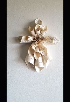 an origami flower made out of book pages on a white wall with text