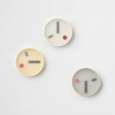 three clocks with different faces are shown on a white surface